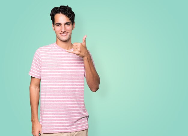 Happy young man making a gesture of calling with the hand