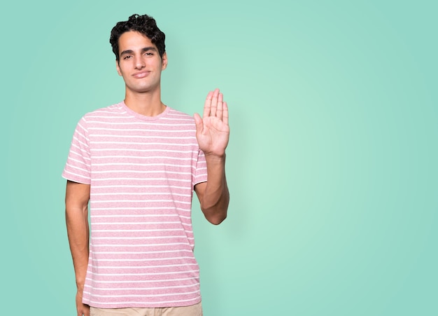 Happy young man making a gesture of stop with his palm