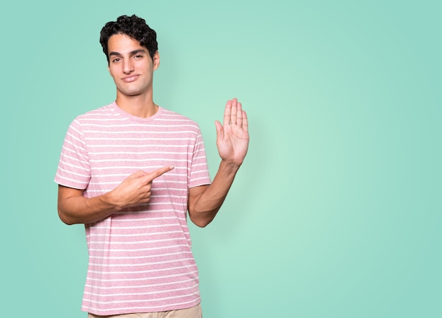 Happy young man making a gesture of stop with his palm