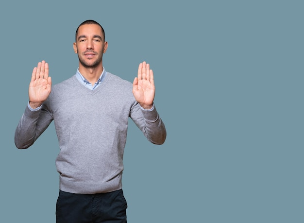 Happy young man making a gesture of stop with his palm