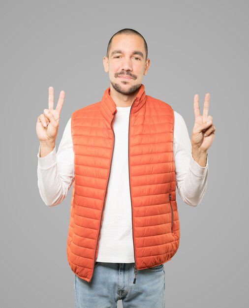 Happy young man making a victory gesture with his fingers