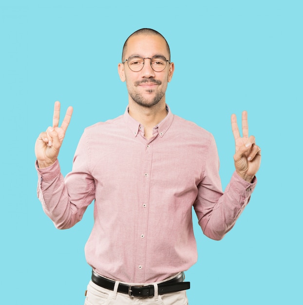 Happy young man making a victory gesture with his fingers