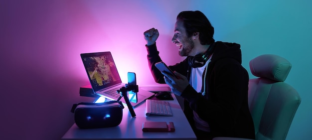 写真 幸せな若い男がコンピュータゲームをしてオンラインストリーミングをしている間手を振っています