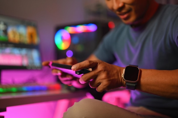 Photo happy young man playing video game on his smartphone at gaming room