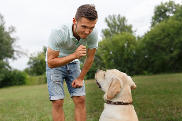 Happy young man playing with dog Labrador outdoors