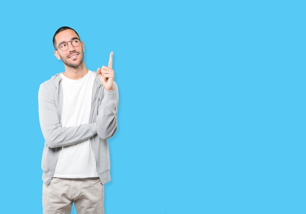 Happy young man pointing up with his finger