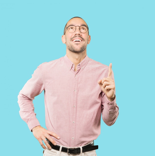 Happy young man pointing up with his finger