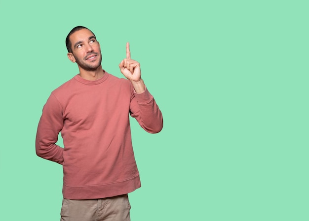 Happy young man pointing up with his finger