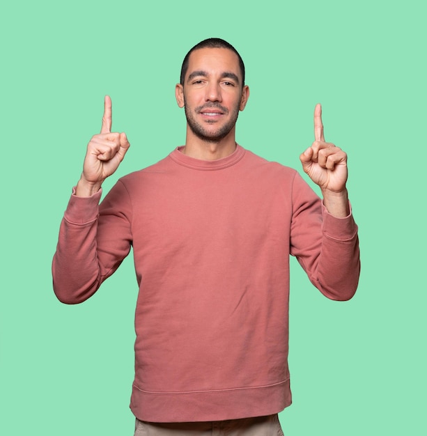 Happy young man pointing up with his finger