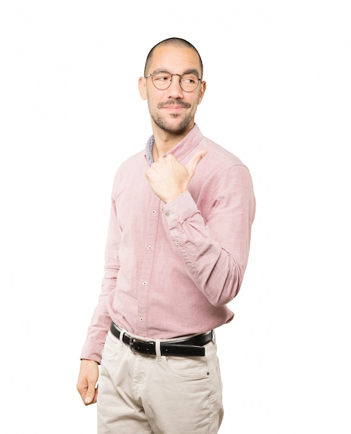 Happy young man pointing with his thumb