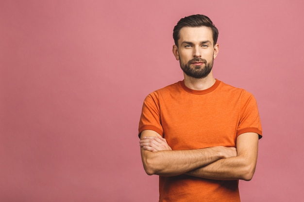 happy young man. portrait of handsome young man in casual keeping arms crossed and smiling while standing against pink wall.