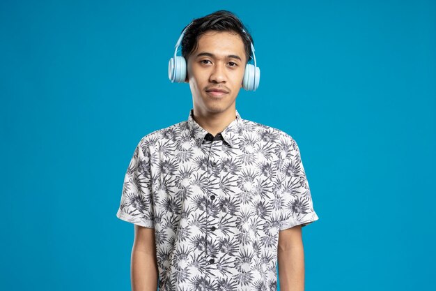 Happy young man posing with headphones on blue.