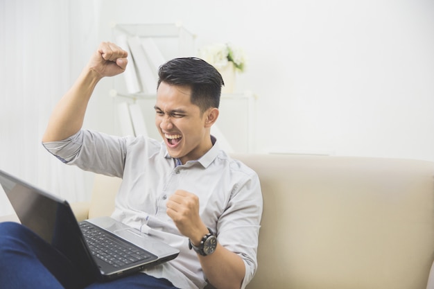 幸せな若い男は彼の手を上げます。成功