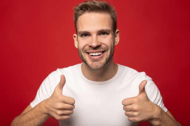 happy young man showing thumbs up isolated on red