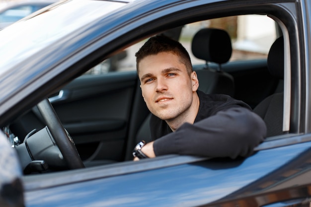 黒い車に座っている幸せな若い男