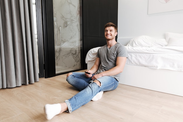 Happy young man sitting with tv remote