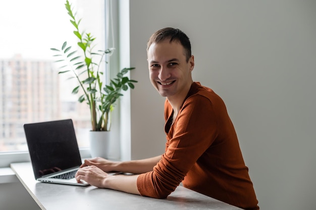 Foto felice giovane, sorridente, mentre lavora sul suo laptop.