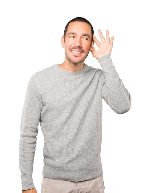 Happy young man smiling and making a gesture of trying to hear something