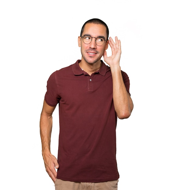 Happy young man smiling and making a gesture of trying to hear something