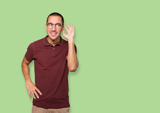 Happy young man smiling and making a gesture of trying to hear something