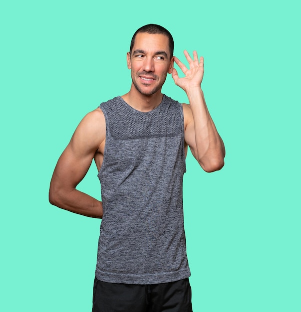 Happy young man smiling and making a gesture of trying to hear something