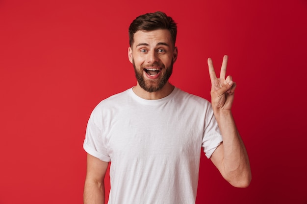 Happy young man standing isolated showing peace gesture.