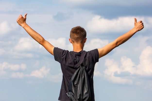 Happy young man standing on top with his hands up