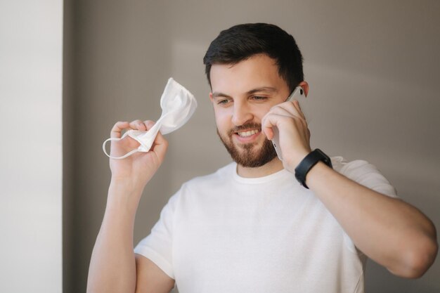 Happy young man take off protective mask end of quarantine
coronavirus theme