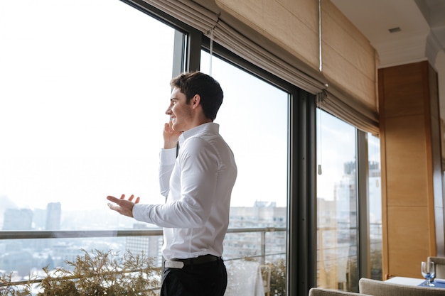 携帯電話で話している幸せな若い男。よそ見。