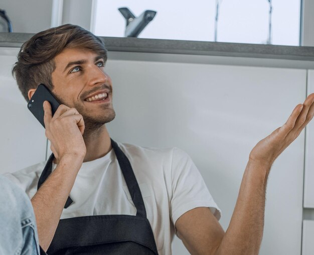 Happy young man talking on mobile phone sitting on floor