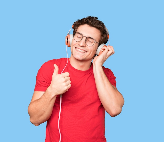 Happy young man using headphones and a smartphone with an okay gesture