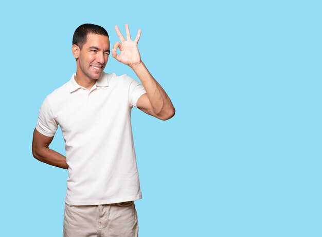 Photo happy young man using his hands like a binoculars