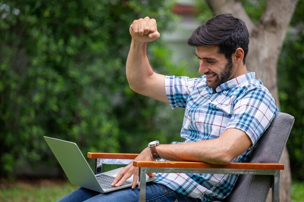 Happy young man using laptop while sitting on chair