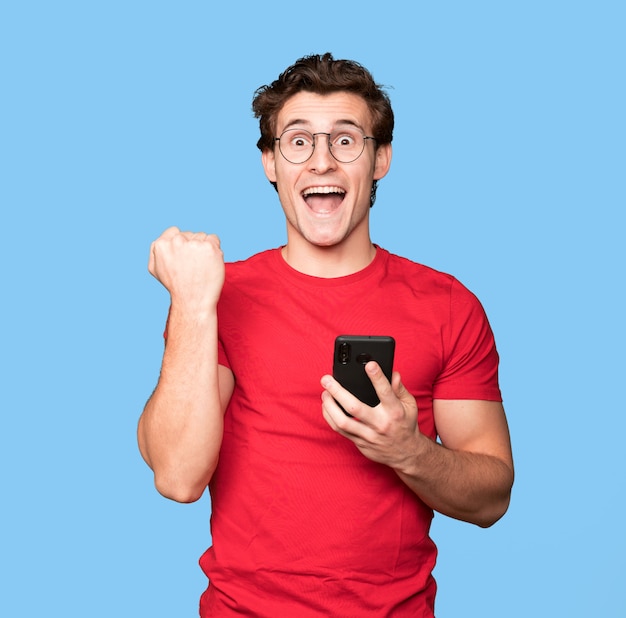 Happy young man using a mobile phone and celebrating