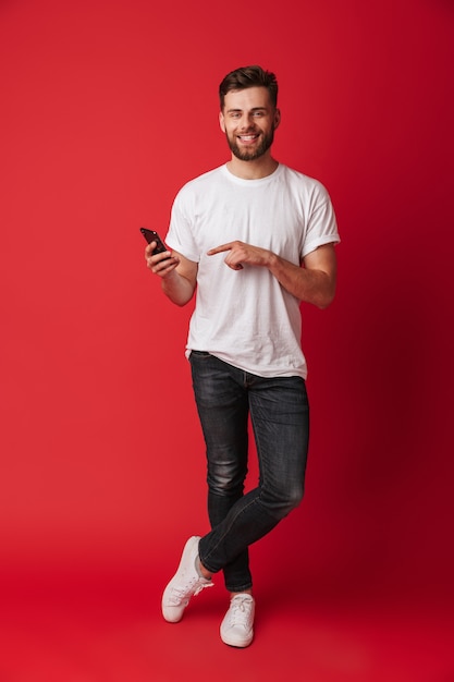 Happy young man using mobile phone pointing.