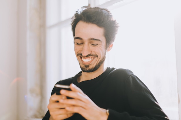 Photo happy young man using smart phone at home