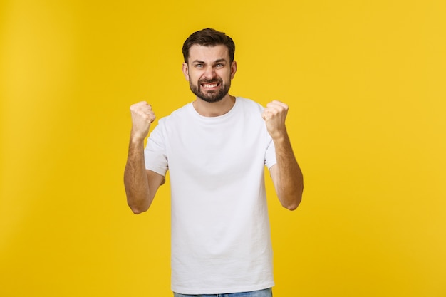 Happy young man with arms up isolated on a yellow