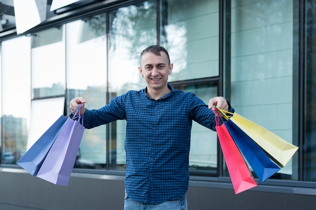 Happy young man with colorful shopping bags on the street