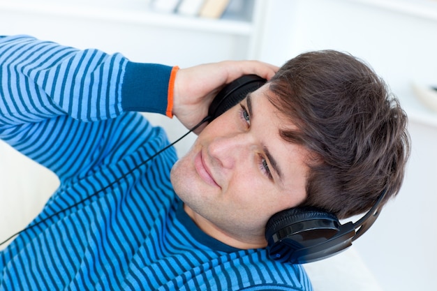 happy young man with headphones relaxing with music on the sofa