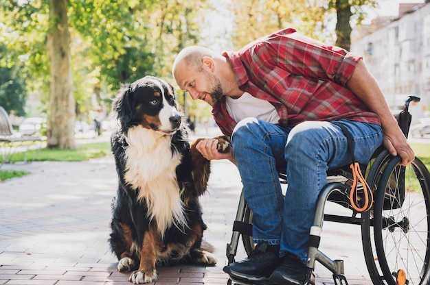 Photo happy young man with a physical disability in a wheelchair with his dog