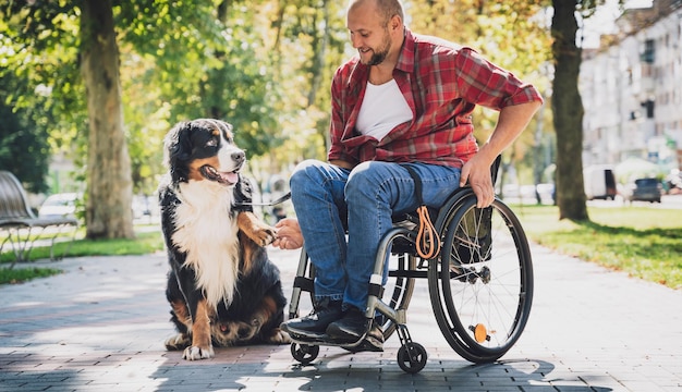 彼の犬と一緒に車椅子で身体障害を持つ幸せな若い男