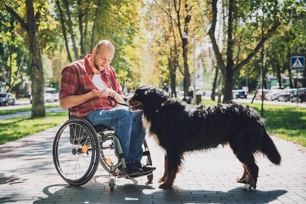 Happy young man with a physical disability in a wheelchair with his dog