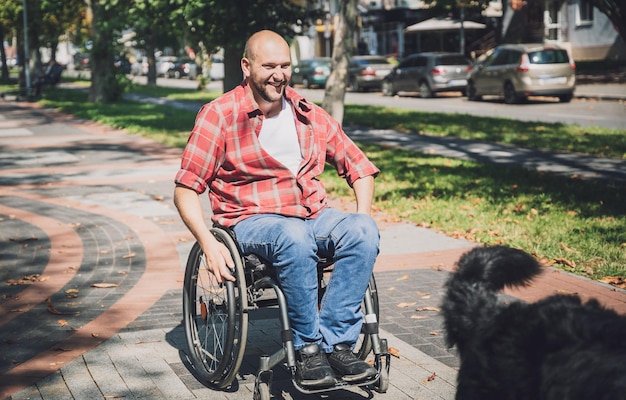 彼の犬と一緒に車椅子で身体障害を持つ幸せな若い男