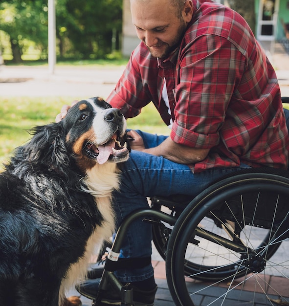 Happy young man with a physical disability who uses wheelchair with his dog