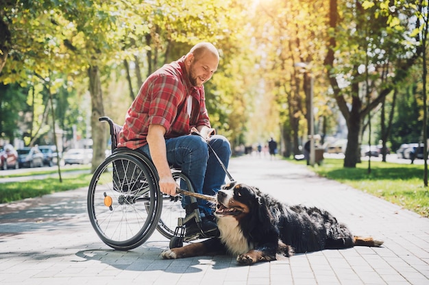 Happy young man with a physical disability who uses wheelchair with his dog