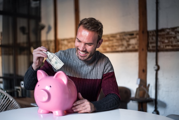 Happy young man with saving piggy bank