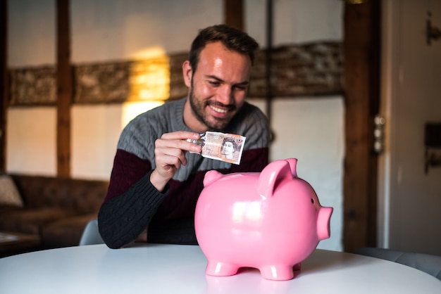 Happy young man with saving piggy bank