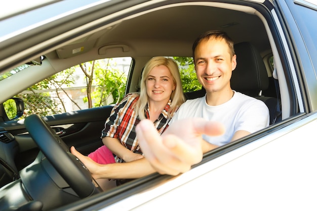 Happy young man and woman in a car enjoying a road trip on a summer day.