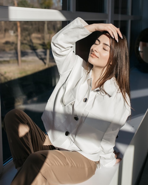 Happy young model posing for photo Girl in stylish clothes The girl smiles and enjoys the sun's rays Outdoor photo