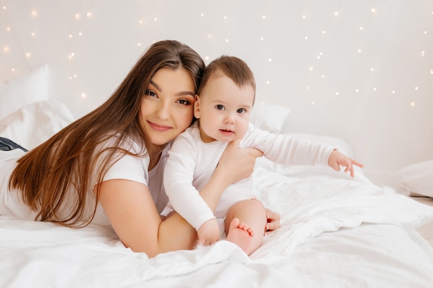 Happy young mom hugs toddler in bed